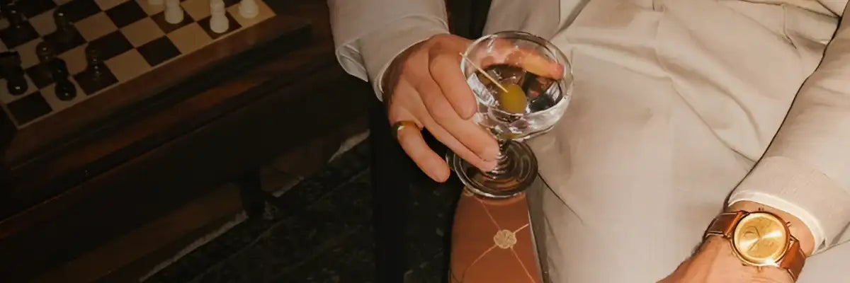 Reloj de oro con correa de cuero marrón y esfera plateada.